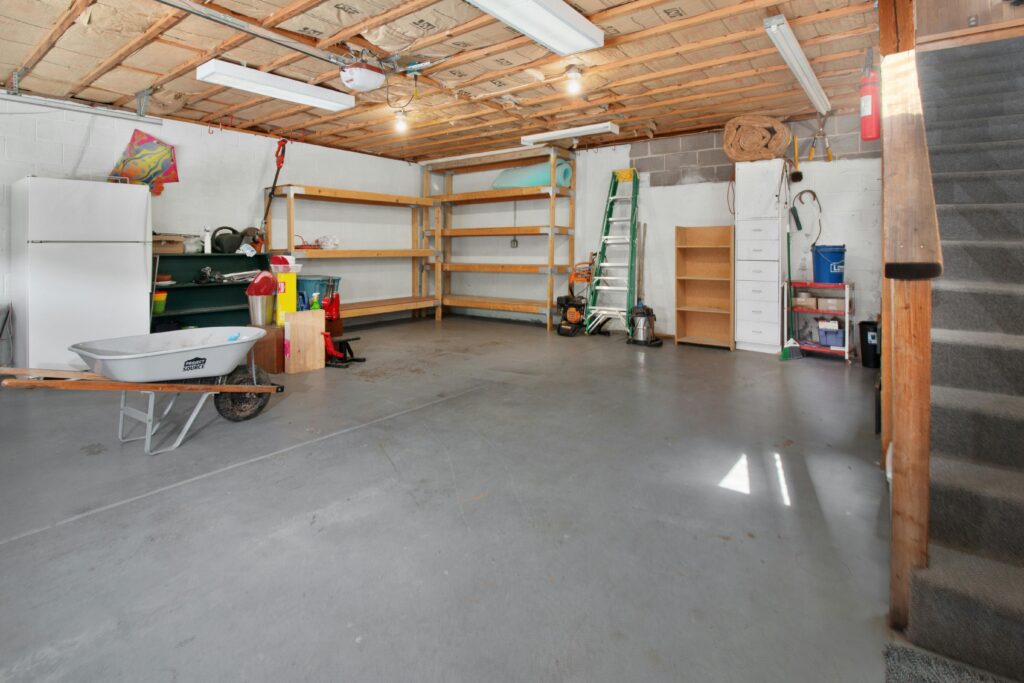 pexels photo 17181949 17181949 Spacious garage interior with storage shelves, tools, and a wheelbarrow, ideal for home organization.